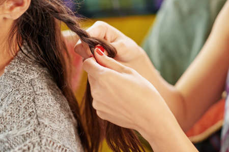 Let me do your hair. a woman braiding her friends hair.