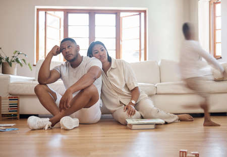 Frustrated stressed african american parents having headache feel tired annoyed about noisy active kids playing at home, upset disturbed mixed race mother and father fatigued of difficult disobedientの写真素材