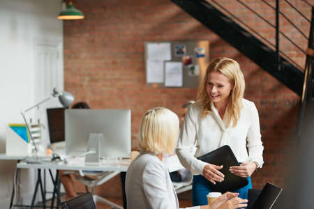 I just came to check in with you. two businesswomen having a discussion in an office.の写真素材