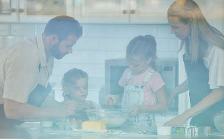 Happy loving family are baking together. Mother, father and two daughters are making cookies and...