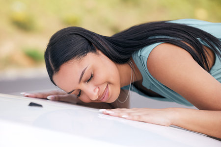 Cheerful mixed race woman loving her new car. Hispanic woman looking happy after buying her first car or after passing her drivers test. Car insuranceの写真素材