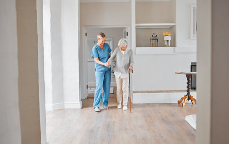 Youre getting stronger by the day. a nurse assisting a senior woman with a walking stick in a retirement home.の写真素材