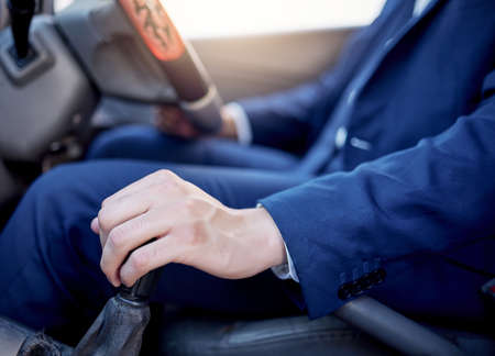 Driving at a safe speed and with caution. Closeup shot of an unidentifiable businessman changing gears while driving a car.の写真素材