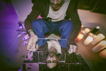 A mixed race man with mental disorder alone at night feeling paranoid. Hispanic sad man mentally ill, depressed and suffering ptsd in his bedroom. Artist having a crisis looking in a cracked mirrorの写真素材