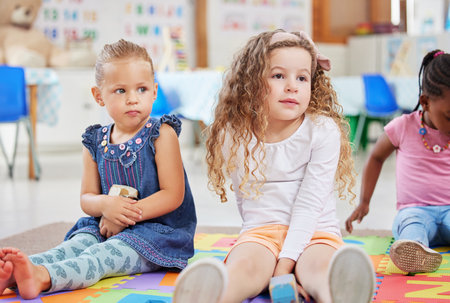 Paying attention in class. two little girls sitting next to each other in class.の写真素材