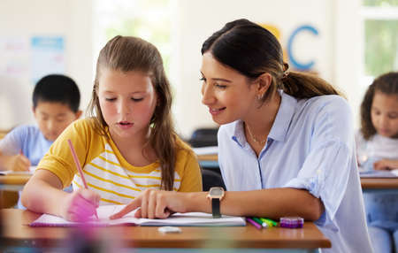 Happy to be in class. a female teacher assisting a preschool learner in her class.の写真素材