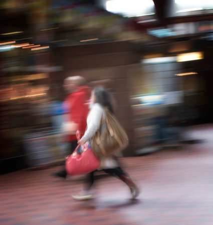 Blurred motion of a couple commuting through an urban town. Man and woman rushing while walking...