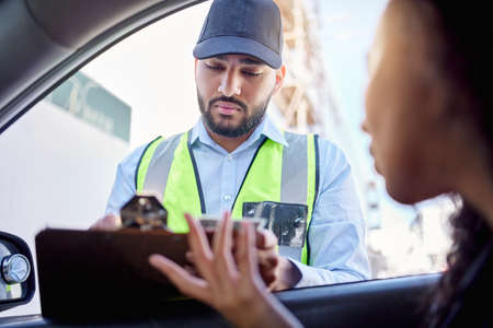 The rules of the road are meant to be followed. Low angle shot of a traffic officer issuing a woman with a ticket.の写真素材