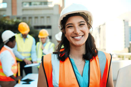 Building is my passion. an attractive young contractor standing outside while her colleagues work behind her.の写真素材