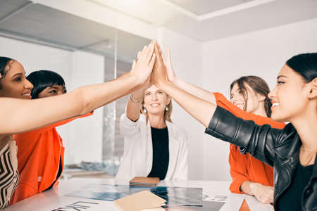 Supporting each other all the way to the top. a group of businesswoman giving each other a high five in an office at work.の写真素材