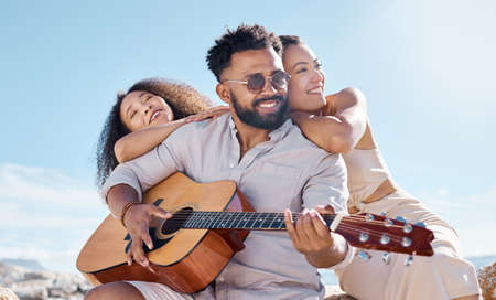 The bond between friends is a special one. a young man playing the guitar while at the beach with his friend.の写真素材