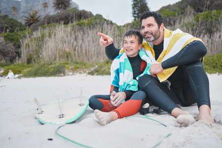 Look at that wave, Dad. a young boy out surfing with his father.の写真素材