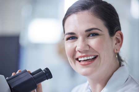 Making the most of her equipment. a young female lab tech using her microscope.の写真素材