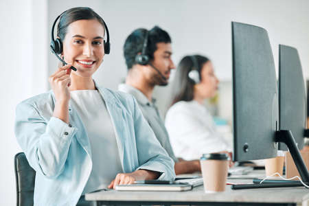 Would you like me to register you on our system. Portrait of a young call centre agent working in an office with her colleagues in the background.の写真素材