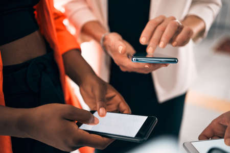 Staying connected, staying updated. a group of unrecognizable businesspeople using their phones...