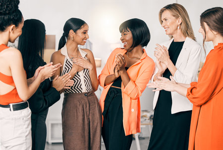 This is the greatest accomplishment. a group of young businesswomen clapping for a coworker at work.の写真素材