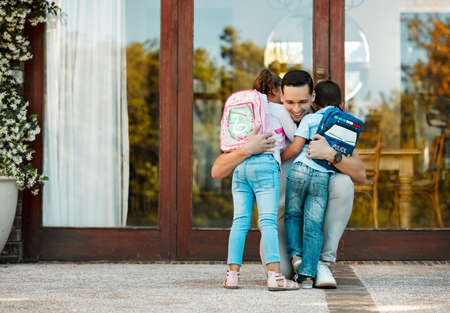 Children returning from school and hugging father on their return. Daddy missed little daughter and...