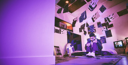 Asian man with mental disorder sitting alone at night and feeling paranoid. Mixed race man mentally ill, feeling depressed in his bedroom. Unemployed Insomniac male sad after a break up with copyspaceの写真素材