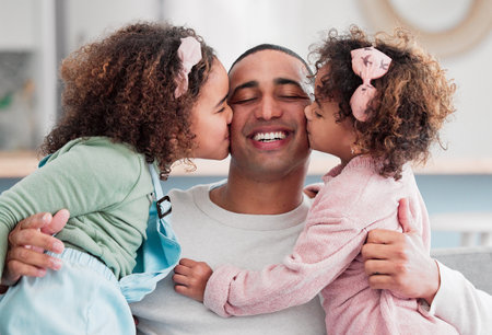 They are the beat of my heart. two little girls giving their father a kiss on the cheek at home.