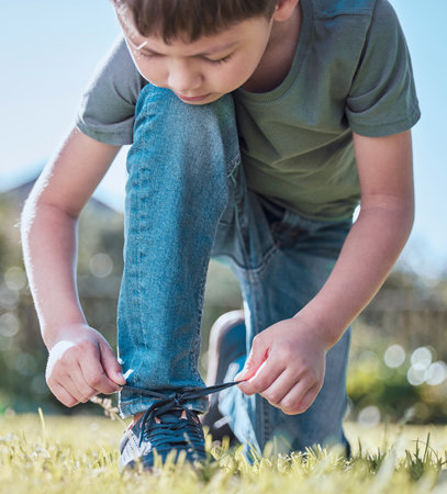 I can tie my own laces, whats next. an adorable little boy tying his shoelaces outside.の写真素材