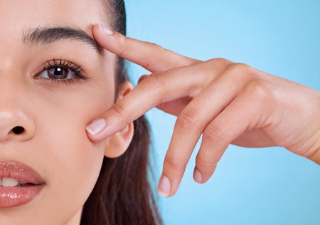 I see you. Studio portrait of an attractive young woman posing against a blue background.の写真素材