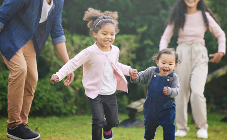 Play is our brains favourite way of learning. two adorable little girls having fun with their family outdoors.の写真素材