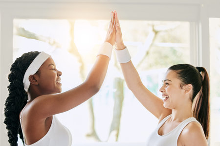 Thats my doubles partner. two attractive young female tennis players high fiving in the clubhouse.の写真素材