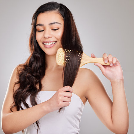 I can do curly or straight and still look good. Studio shot of a young woman brushing her hair.の写真素材