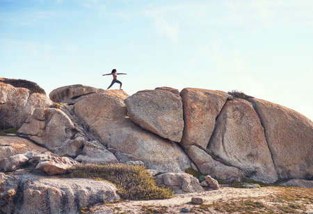Awaken the warrior within you. a young woman practicing yoga on a boulder.の写真素材