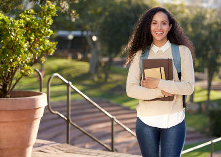 A taste of being an adult. Portrait of an attractive young female student standing outside on campus.の写真素材