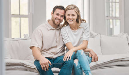 You stole my heart but Ill let you keep it. a young couple sitting on the sofa at home.の写真素材