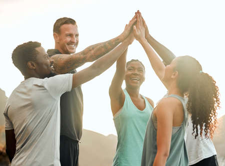 Cheers to having great workout partners. a group of friends high fiving one another before a workout.の写真素材