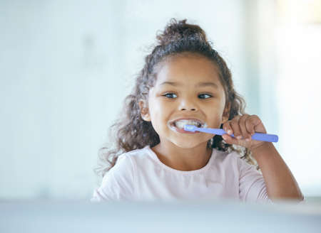 Taking good care of my teeth. a little girl brushing her teeth in a bathroom at home.の写真素材