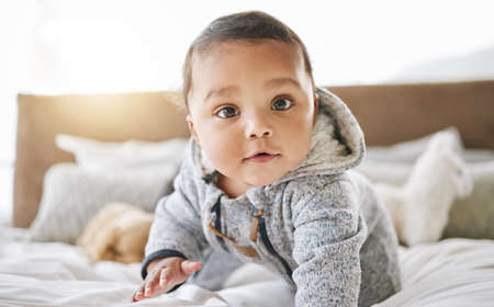Watch me do my thing. an adorable baby boy playing on the bed at home.