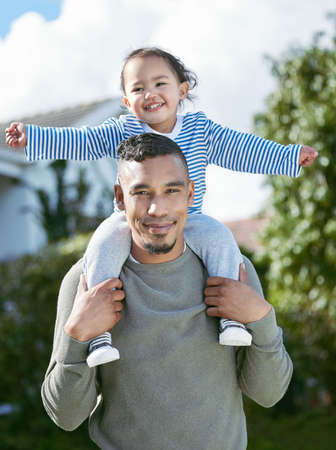 Family is everything to me. a young man carrying his daughter on his shoulders.の写真素材