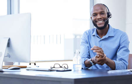 The friendliest call center agent. a young male call center agent working in an office.