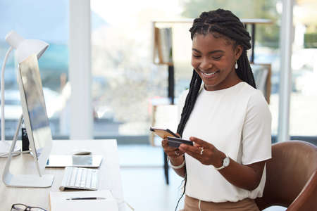 a young businesswoman using a credit card and phone at work.