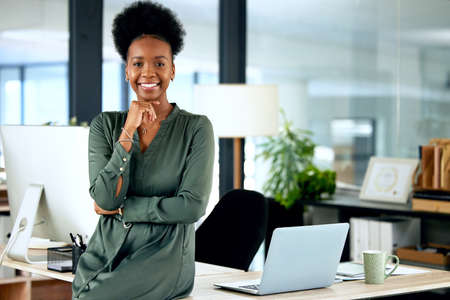 Being your own boss is so rewarding. a young businesswoman standing in an office at work.の写真素材