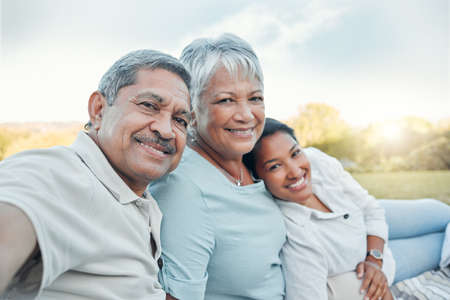 Keep your family and close friends close. a woman taking a selfie with her parents in a park.の写真素材