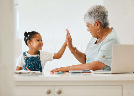 You got that right. a grandma helping her granddaughter at the kitchen table at home.の写真素材