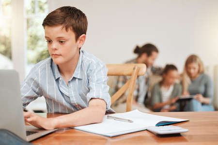 Well support you from back here. a young boy doing his homework at the kitchen table at home.の写真素材