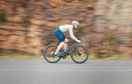 Thats some serious speed. Full length shot of a handsome mature man cycling outdoors.の写真素材