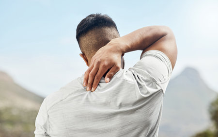 a sporty young man experiencing discomfort in his neck while out for a run.の写真素材