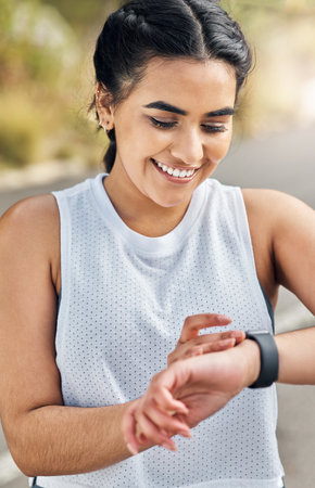 a young woman checking her watch while out for a run.の写真素材