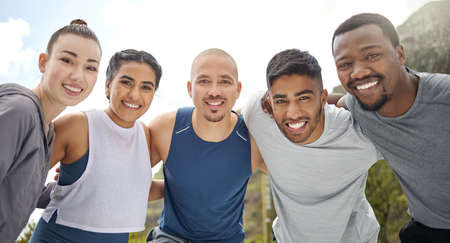 No one gets left behind on this journey. Portrait of a group of sporty young people standing together in a huddle while exercising outdoors.の写真素材