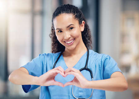 Ill take good care of you. a young female doctor making a heart gesture with her hands at a hospital.の写真素材