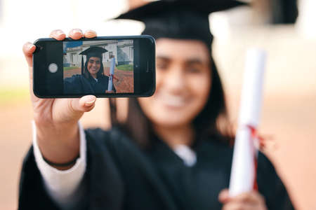 a female graduate taking selfies using her smartphone.の写真素材