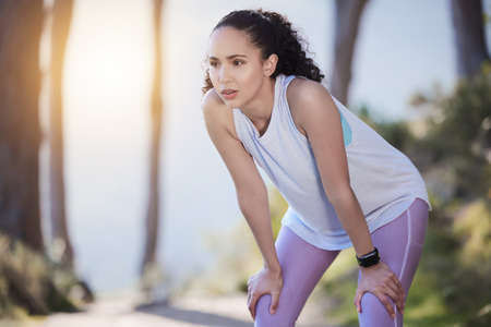 a sporty young woman resting her hands on her knees.
