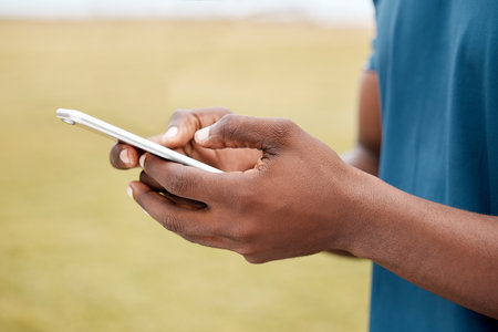 I have my own digital personal trainer. Closeup shot of an unrecognisable man using a cellphone while exercising outdoors.の写真素材