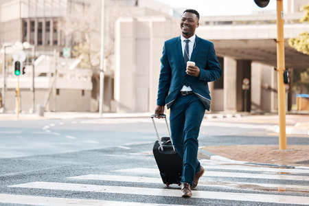 Ready to take the trip of a lifetime. a young businessman drinking coffee while walking to the airport.の写真素材
